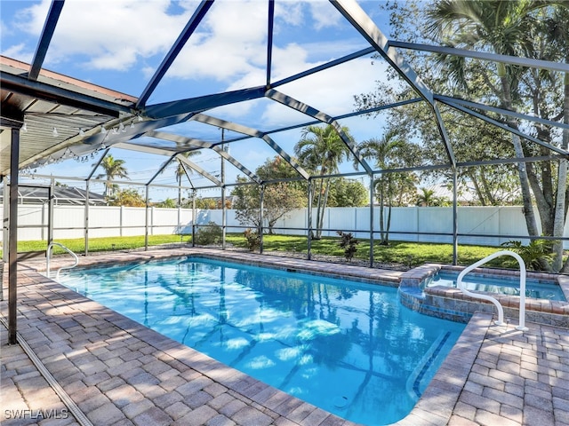 view of pool with glass enclosure, a patio area, a fenced backyard, and a pool with connected hot tub