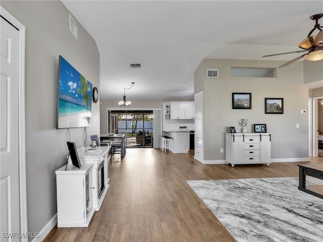 living area with visible vents, dark wood finished floors, and ceiling fan with notable chandelier