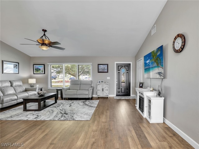 living area with visible vents, a ceiling fan, wood finished floors, baseboards, and lofted ceiling