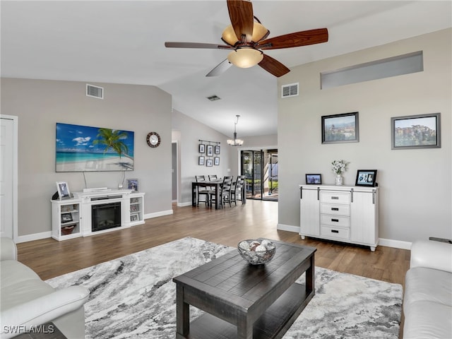 living room featuring visible vents, ceiling fan with notable chandelier, lofted ceiling, and wood finished floors