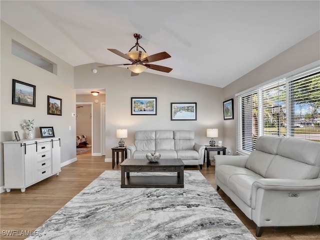 living room featuring baseboards, wood finished floors, a ceiling fan, and vaulted ceiling