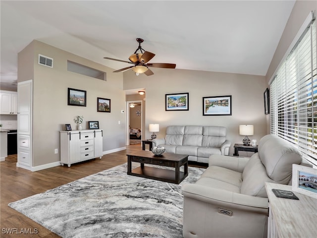 living room featuring visible vents, baseboards, lofted ceiling, a ceiling fan, and dark wood-style flooring