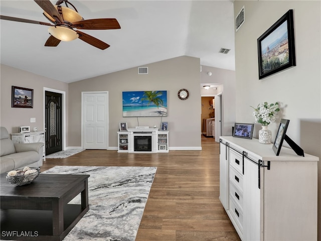 living room featuring a ceiling fan, vaulted ceiling, wood finished floors, and visible vents