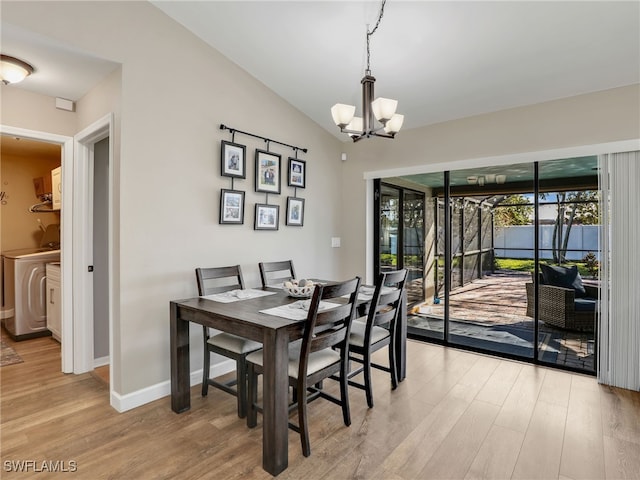 dining area with baseboards, light wood-type flooring, vaulted ceiling, washer / dryer, and a notable chandelier