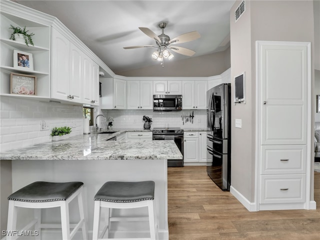 kitchen with electric range, a sink, stainless steel microwave, freestanding refrigerator, and a peninsula