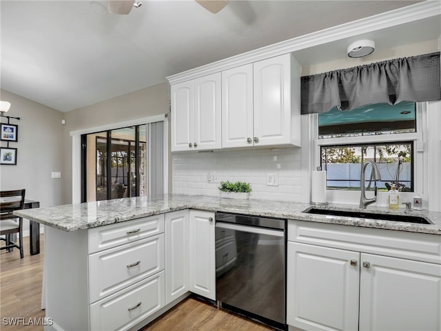 kitchen featuring light wood-style flooring, dishwasher, a peninsula, and a sink