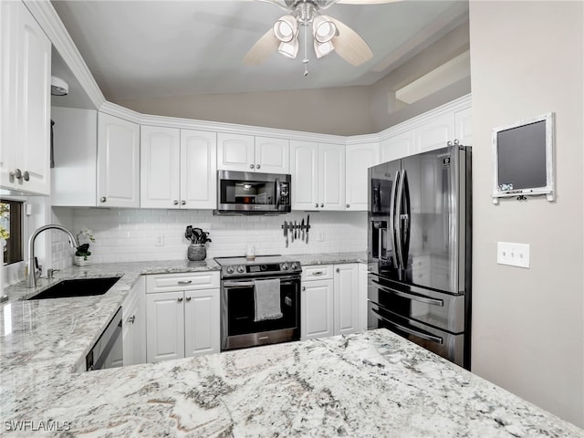 kitchen featuring ceiling fan, vaulted ceiling, white cabinets, stainless steel appliances, and a sink