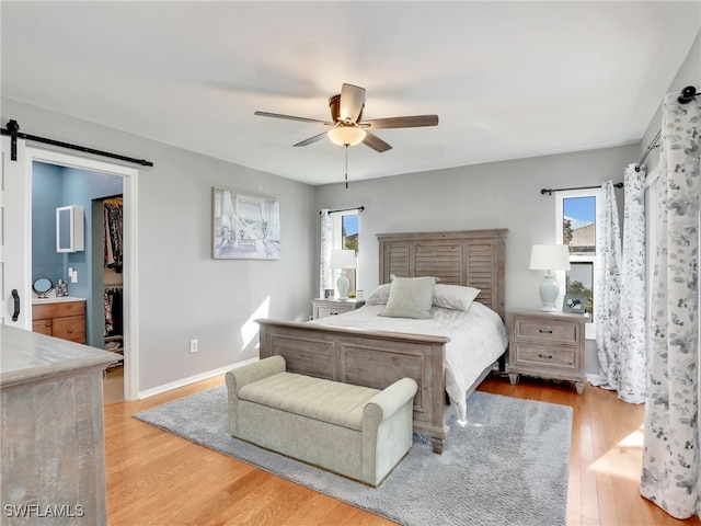 bedroom featuring a walk in closet, multiple windows, wood finished floors, and baseboards