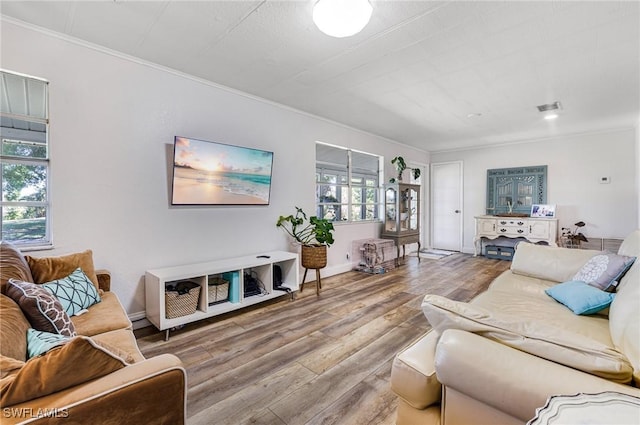 living room featuring visible vents, baseboards, wood finished floors, and ornamental molding