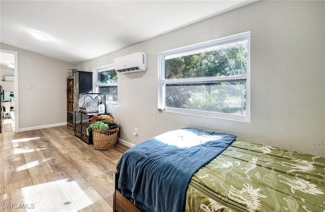 bedroom featuring baseboards, an AC wall unit, and light wood finished floors