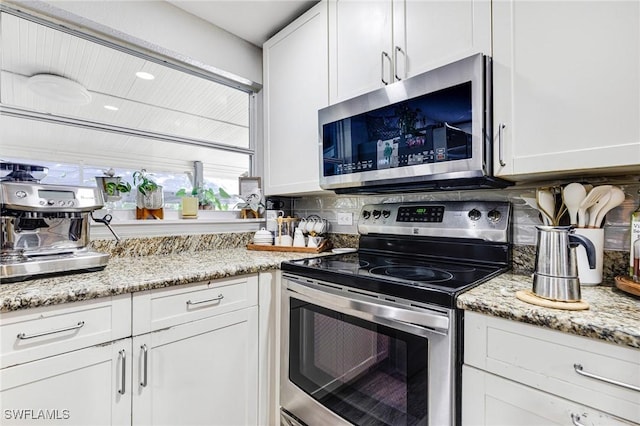 kitchen featuring white cabinetry, decorative backsplash, light stone counters, and appliances with stainless steel finishes