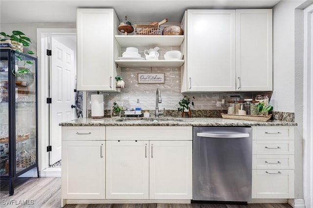 kitchen featuring light stone countertops, open shelves, a sink, stainless steel dishwasher, and backsplash