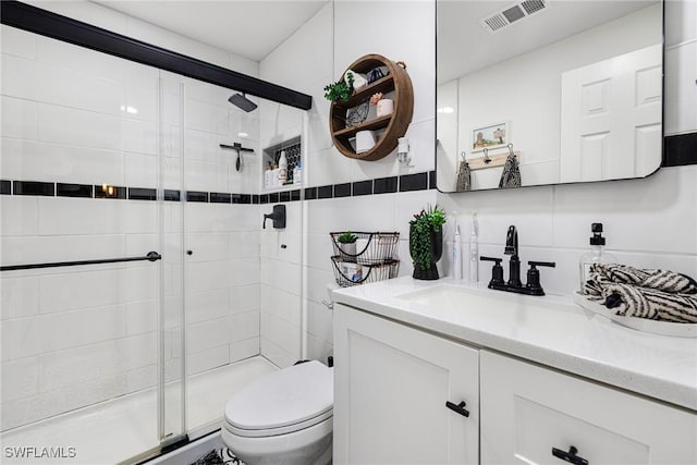 full bath with vanity, visible vents, a shower stall, tile walls, and toilet