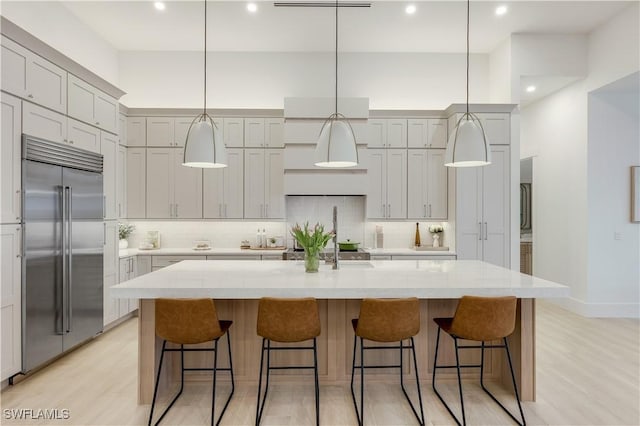 kitchen with backsplash, built in fridge, and light wood finished floors