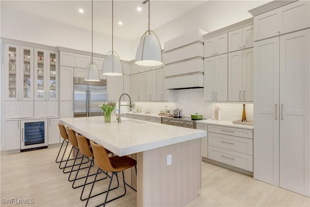 kitchen with backsplash, stainless steel built in refrigerator, wine cooler, a kitchen bar, and range