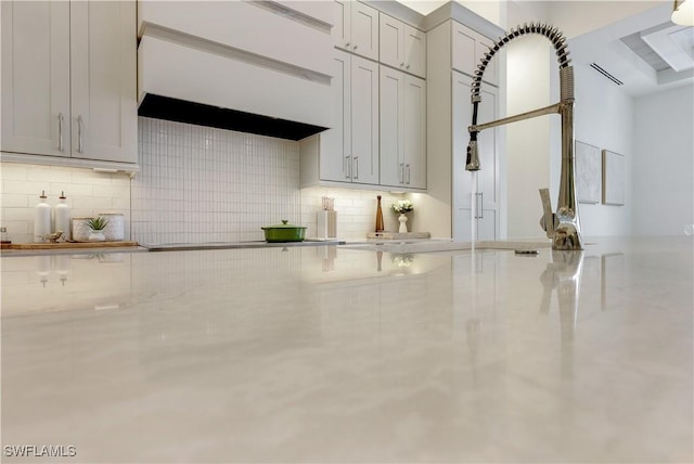 kitchen featuring cooktop, custom exhaust hood, and tasteful backsplash