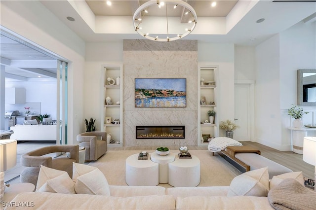 living room featuring wood finished floors, built in features, a fireplace, and baseboards