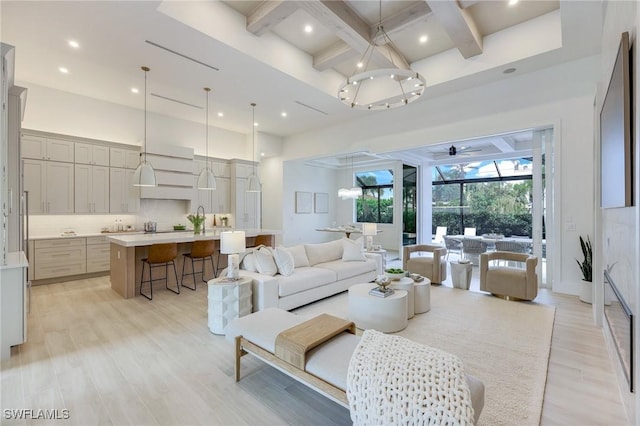 living area featuring a chandelier, beamed ceiling, light wood-style flooring, a towering ceiling, and coffered ceiling