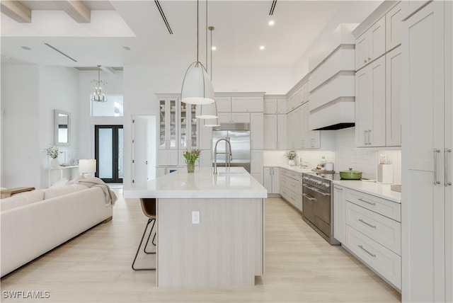 kitchen featuring premium appliances, tasteful backsplash, open floor plan, a breakfast bar area, and light countertops