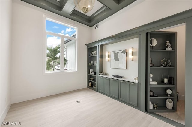 interior space featuring light wood-style flooring, built in shelves, visible vents, and coffered ceiling