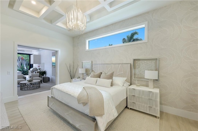 bedroom featuring wallpapered walls, baseboards, light wood-type flooring, an inviting chandelier, and coffered ceiling