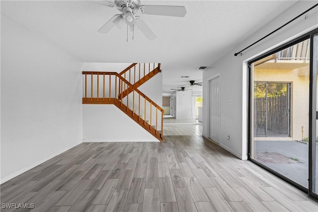 unfurnished living room featuring stairs, baseboards, visible vents, and wood tiled floor