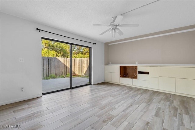 unfurnished living room with light wood-type flooring, baseboards, a textured ceiling, and a ceiling fan