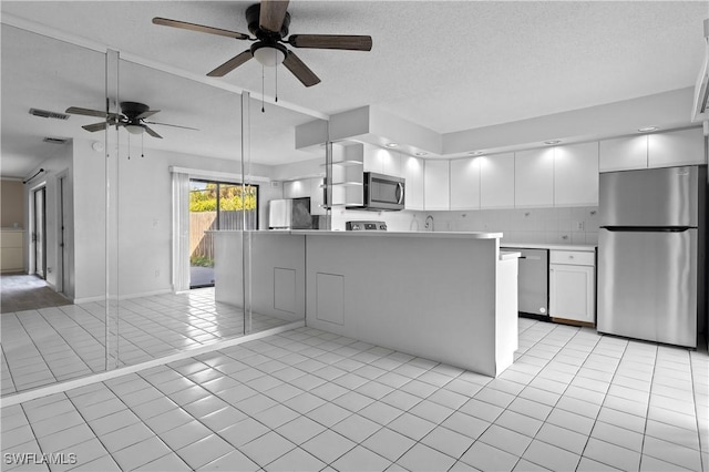 kitchen featuring appliances with stainless steel finishes, light tile patterned flooring, white cabinets, and light countertops