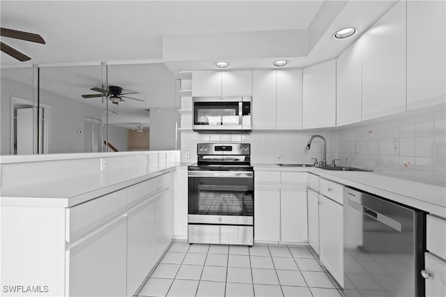 kitchen with backsplash, light countertops, a peninsula, stainless steel appliances, and a sink