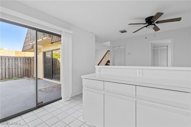 spare room featuring light tile patterned floors, visible vents, ceiling fan, and stairs