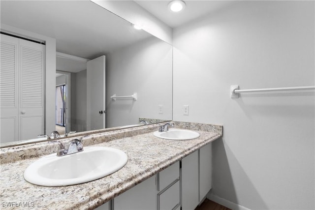 full bathroom with double vanity, baseboards, a closet, and a sink