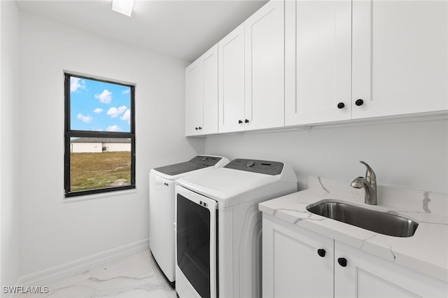 clothes washing area with baseboards, cabinet space, a sink, marble finish floor, and washer and clothes dryer