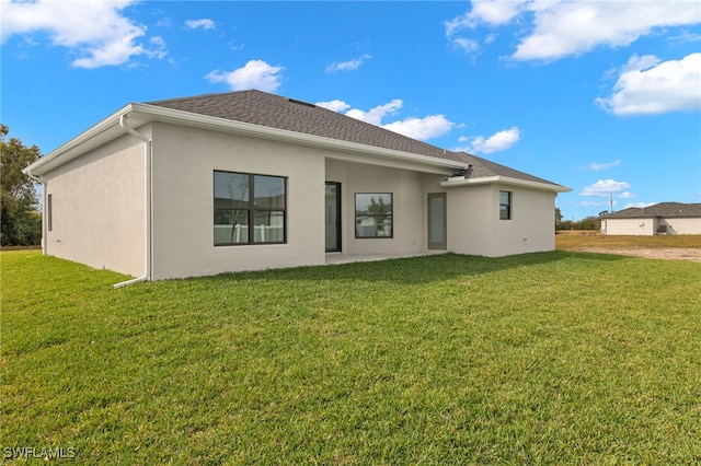 rear view of property featuring stucco siding and a yard