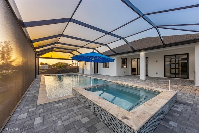 view of swimming pool featuring a patio area, glass enclosure, and a pool with connected hot tub