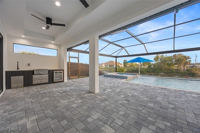 view of patio featuring a pool with connected hot tub, glass enclosure, a grill, exterior kitchen, and ceiling fan