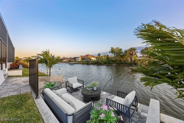 patio terrace at dusk featuring outdoor lounge area and a water view