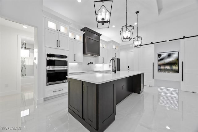 kitchen with stainless steel double oven, marble finish floor, a barn door, and a sink