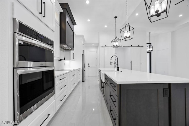 kitchen with appliances with stainless steel finishes, white cabinetry, light countertops, and a barn door