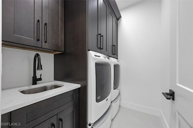 laundry area featuring baseboards, cabinet space, independent washer and dryer, and a sink