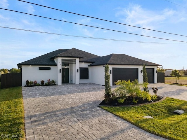 view of front of home featuring fence, a front yard, stucco siding, decorative driveway, and an attached garage