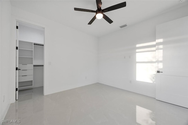 unfurnished bedroom featuring ceiling fan, visible vents, a closet, and a walk in closet