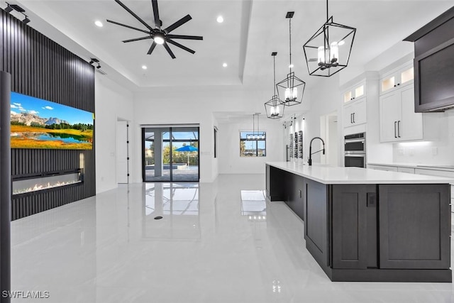 kitchen with a spacious island, light countertops, a glass covered fireplace, double oven, and open floor plan