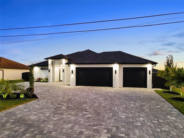 view of front of house featuring stucco siding, an attached garage, and decorative driveway