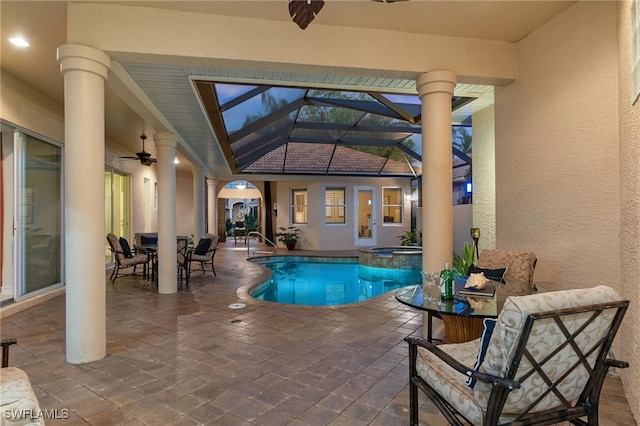 view of pool with a pool with connected hot tub, glass enclosure, a patio, outdoor dining space, and a ceiling fan