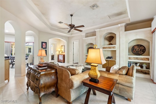 living room featuring arched walkways, visible vents, a raised ceiling, and a ceiling fan