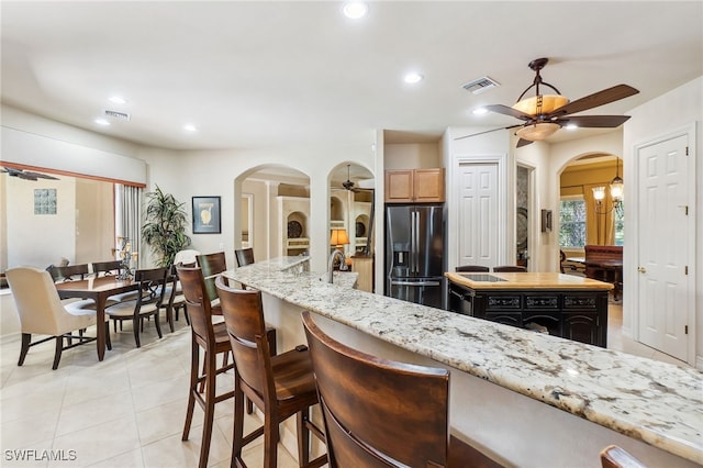 kitchen featuring a ceiling fan, visible vents, arched walkways, and stainless steel fridge