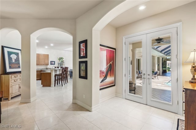 foyer with baseboards, light tile patterned flooring, recessed lighting, arched walkways, and french doors