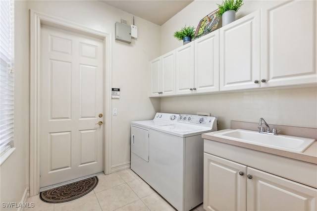 washroom with baseboards, light tile patterned floors, cabinet space, independent washer and dryer, and a sink