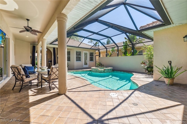 view of pool featuring glass enclosure, a patio, a pool with connected hot tub, and ceiling fan