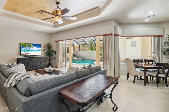 living area featuring visible vents, a tray ceiling, light tile patterned flooring, ceiling fan, and crown molding